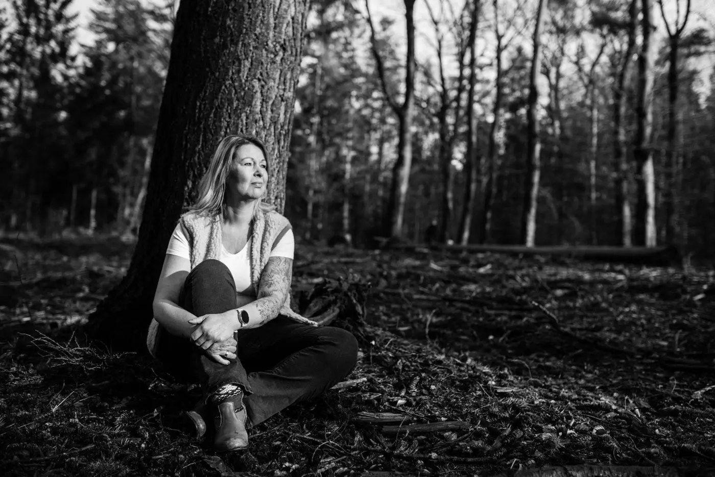 Willanda zit tegen een boom in het bos, zwart-wit