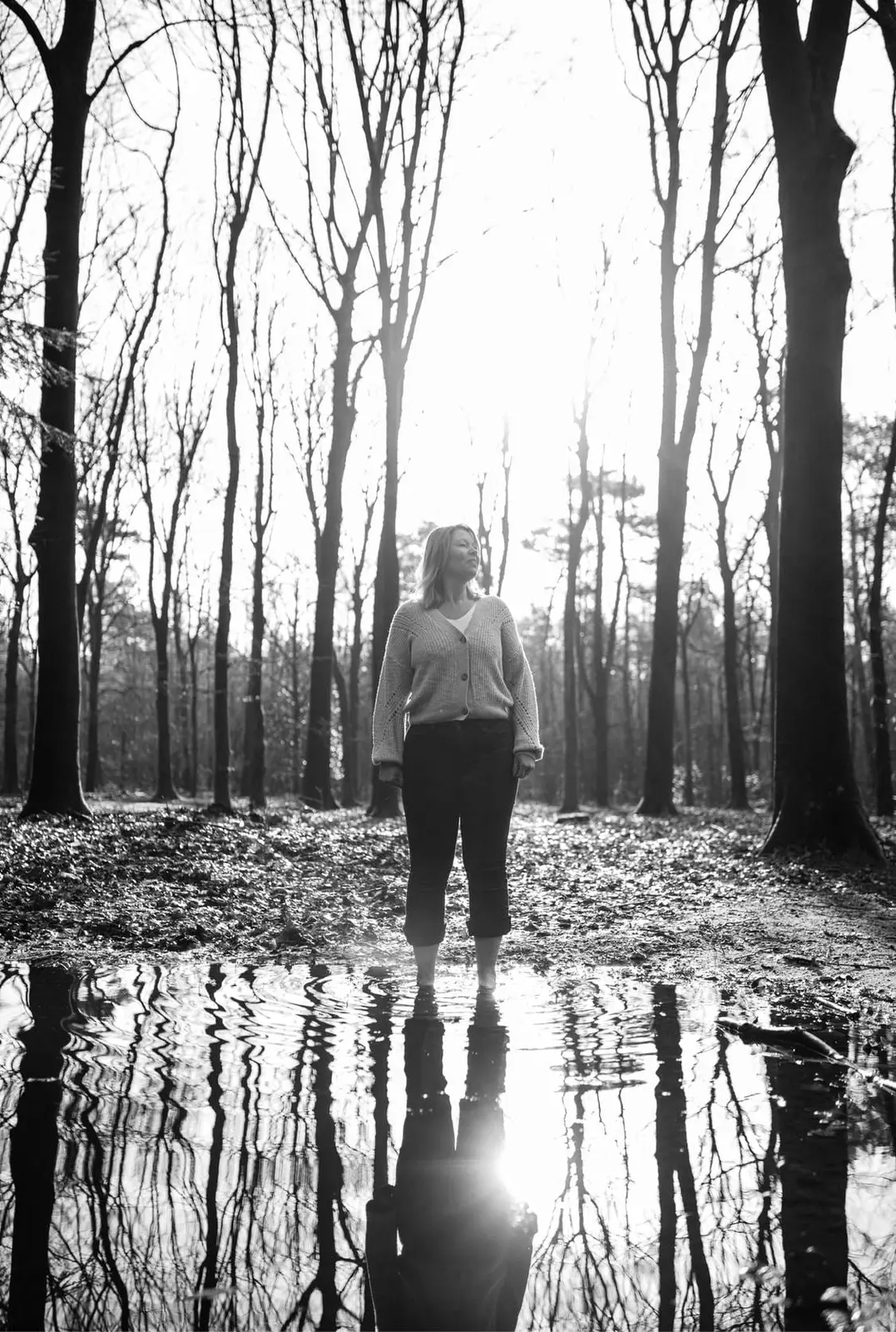 Willanda staat in het bos aan de rand van een plas, haar spiegelbeeld in het water