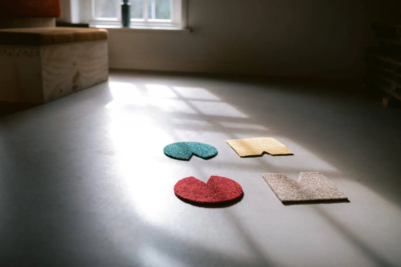 Vier gekleurde vormen op een houten vloer in een baan zonlicht